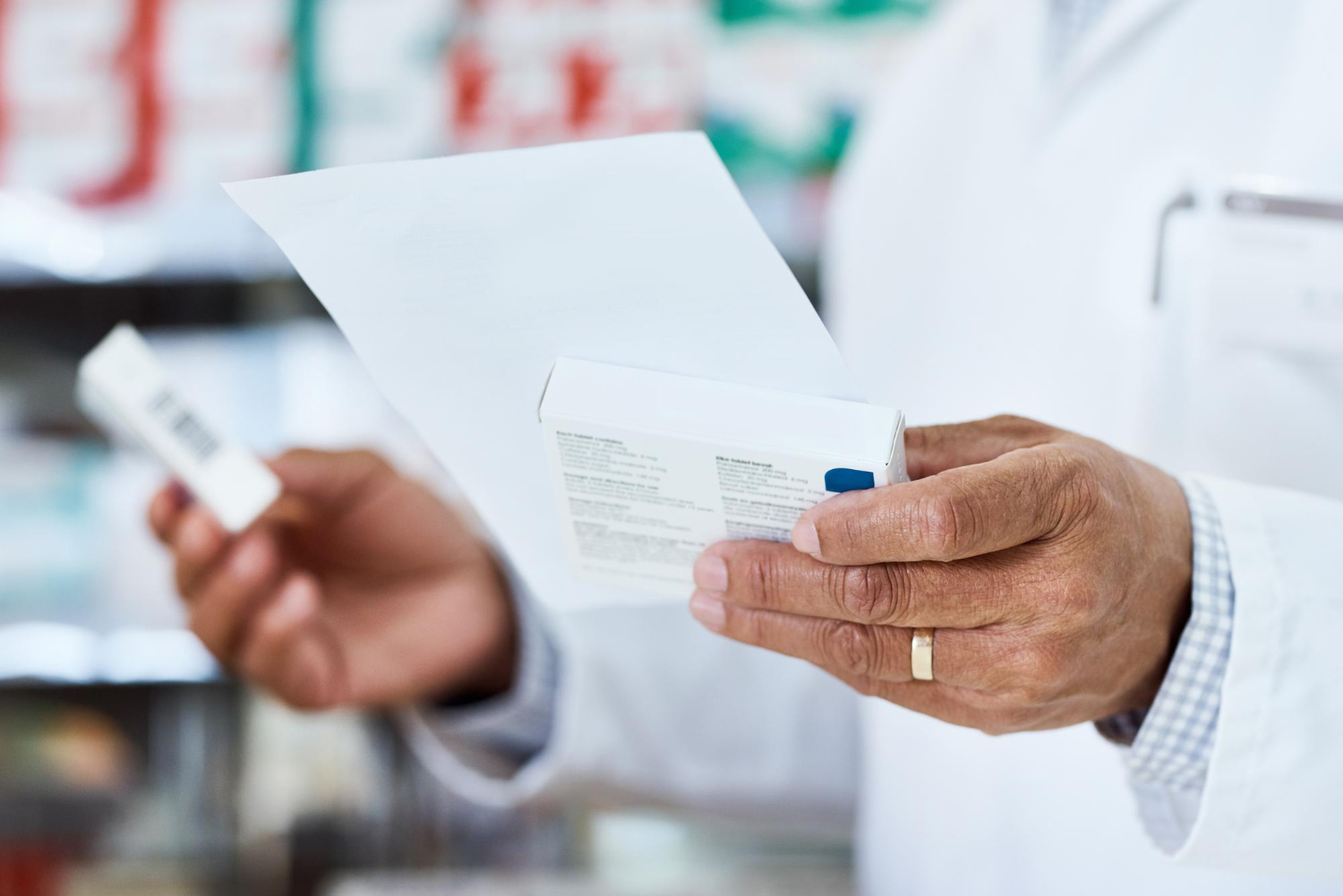 507154 A pharmacist checks medication packaging and a prescription in a pharmacy.